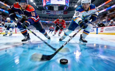 NHL季后赛激烈比赛现场，球员在冰面上高速滑行争抢冰球